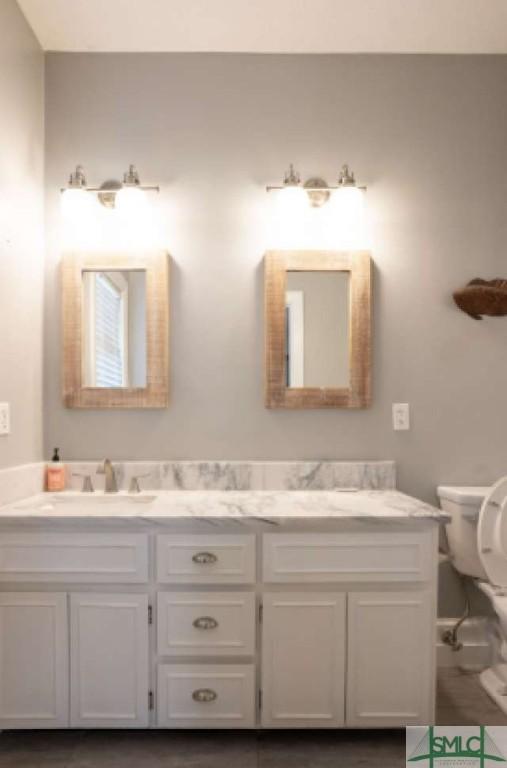 bathroom with a sink, toilet, and double vanity