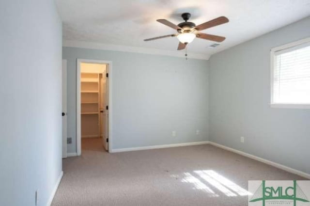 unfurnished bedroom featuring ceiling fan, a walk in closet, carpet, baseboards, and a closet