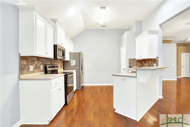 kitchen with kitchen peninsula, white cabinets, tasteful backsplash, dark hardwood / wood-style flooring, and stainless steel appliances