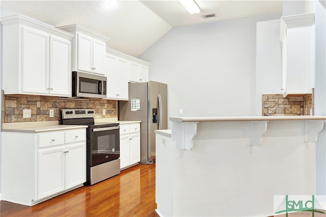 kitchen featuring white cabinets, a kitchen bar, and stainless steel appliances