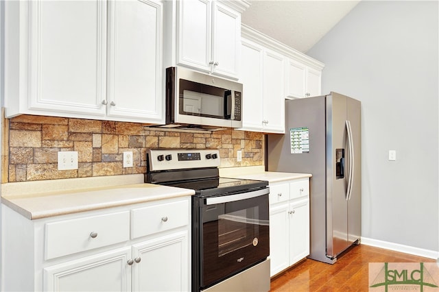 kitchen featuring appliances with stainless steel finishes, light hardwood / wood-style flooring, white cabinetry, and lofted ceiling