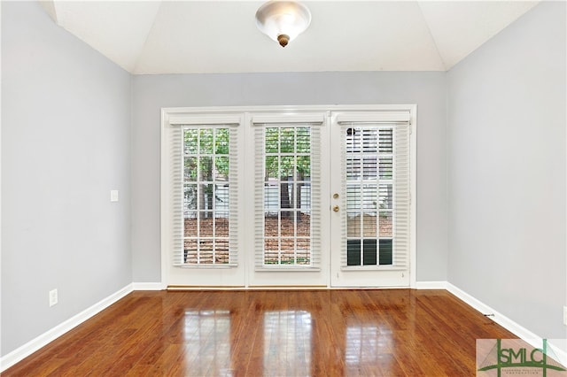 spare room with hardwood / wood-style flooring and lofted ceiling