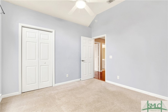 unfurnished bedroom with light carpet, a closet, vaulted ceiling, and ceiling fan