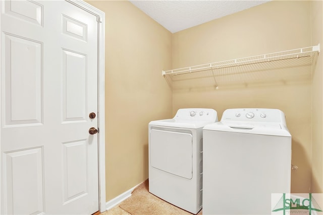 clothes washing area with a textured ceiling, light colored carpet, and washing machine and dryer