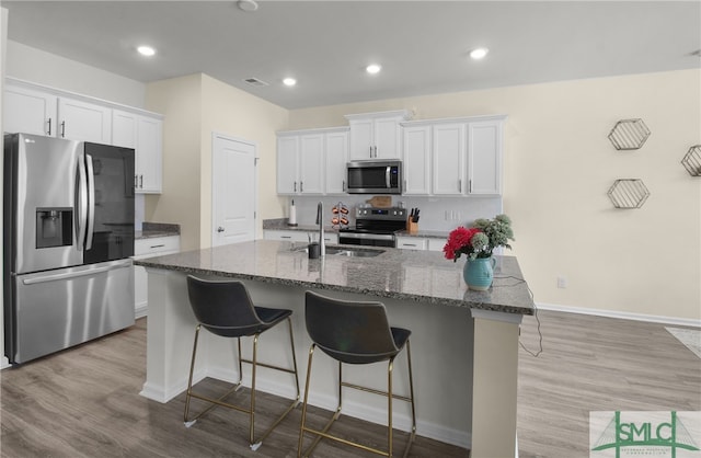 kitchen featuring sink, appliances with stainless steel finishes, a kitchen island with sink, and white cabinets