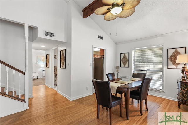 dining area with beam ceiling, ceiling fan, high vaulted ceiling, a textured ceiling, and light wood-type flooring