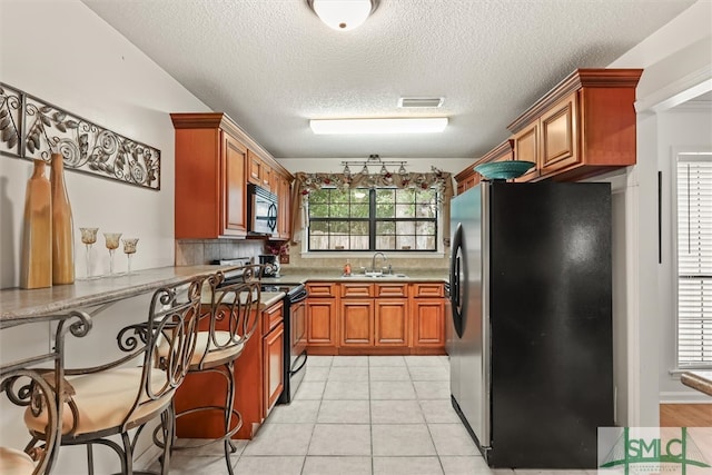 kitchen featuring backsplash, a wealth of natural light, light tile patterned floors, and stainless steel appliances