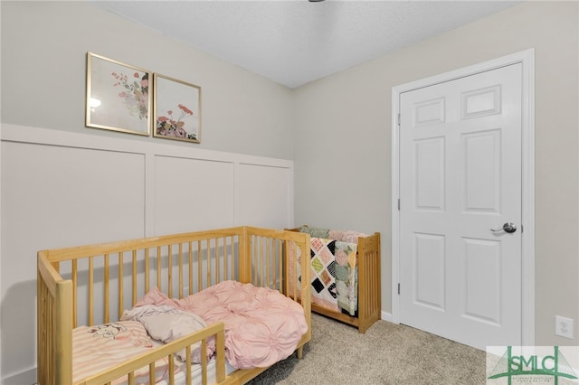 carpeted bedroom with a textured ceiling and a crib