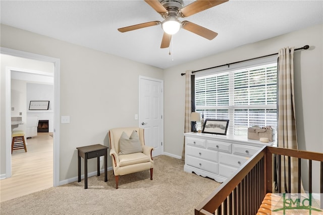 carpeted bedroom with ceiling fan and a nursery area