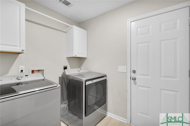 laundry room with cabinets, independent washer and dryer, and light hardwood / wood-style floors