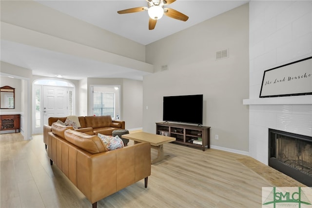 living room featuring ceiling fan, light wood-type flooring, and a fireplace