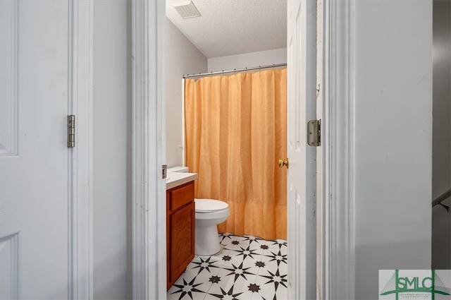 bathroom featuring a textured ceiling, vanity, toilet, and walk in shower