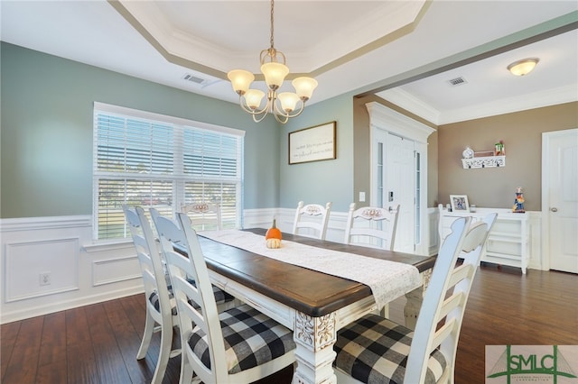 dining space featuring ornamental molding, dark hardwood / wood-style floors, an inviting chandelier, and a raised ceiling