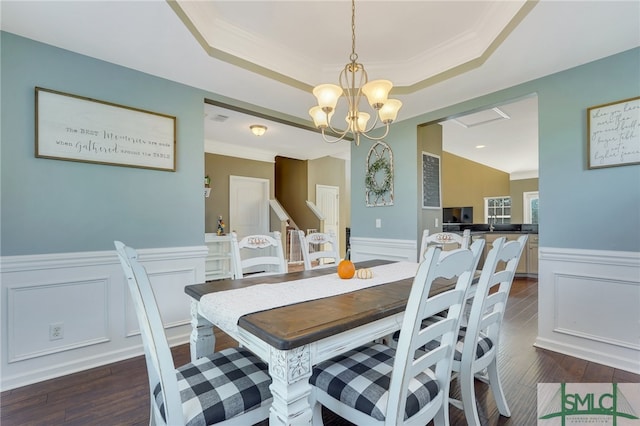 dining area with a notable chandelier, ornamental molding, a tray ceiling, and dark hardwood / wood-style flooring