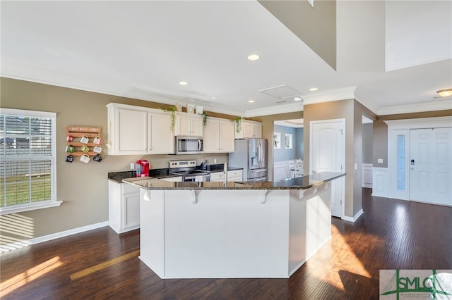 kitchen featuring dark stone countertops, stainless steel appliances, a kitchen bar, and a kitchen island