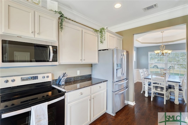 kitchen with dark hardwood / wood-style flooring, stainless steel appliances, dark stone countertops, crown molding, and an inviting chandelier