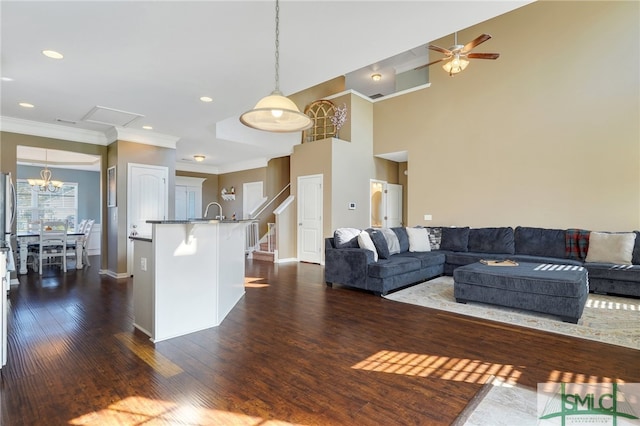 living room with crown molding, dark wood-type flooring, a high ceiling, and ceiling fan