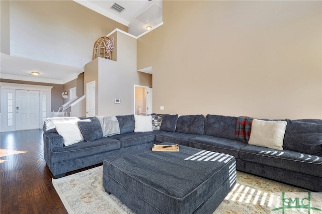 living room with dark wood-type flooring, crown molding, and a high ceiling