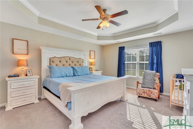 bedroom with ornamental molding, carpet, a tray ceiling, and ceiling fan