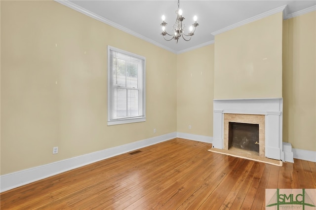 unfurnished living room featuring an inviting chandelier, hardwood / wood-style floors, a tile fireplace, and crown molding