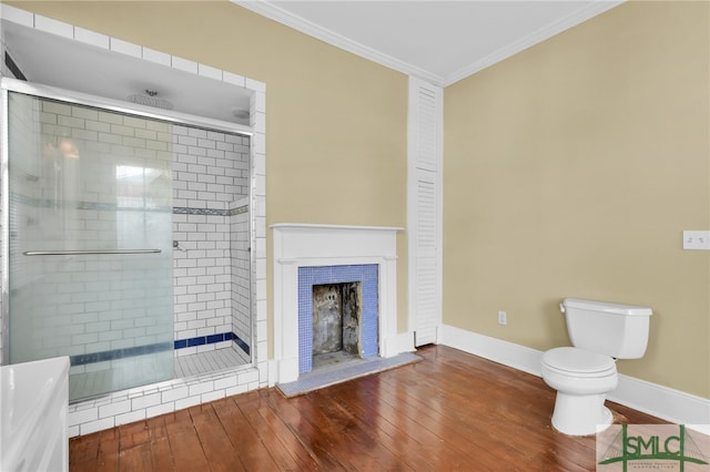 bathroom featuring toilet, a shower with door, hardwood / wood-style floors, ornamental molding, and a fireplace