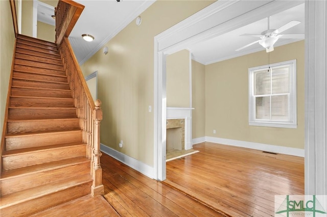 124 Brady St, Savannah, GA 31401 - stairway with ornamental molding, hardwood / wood-style floors, baseboards, ceiling fan, and a fireplace