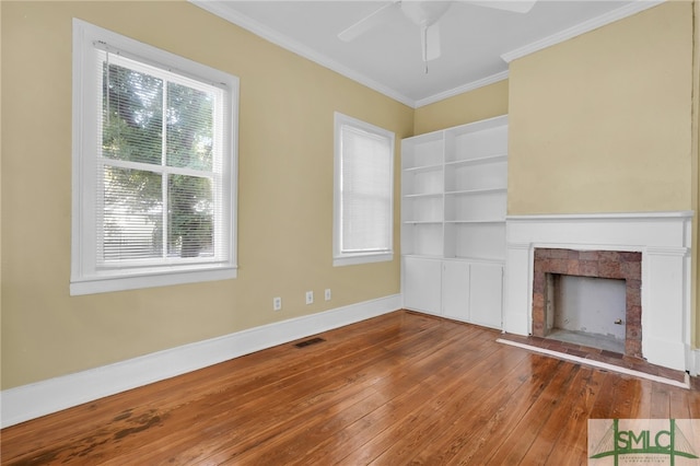 unfurnished living room featuring ceiling fan, hardwood / wood-style floors, crown molding, and plenty of natural light