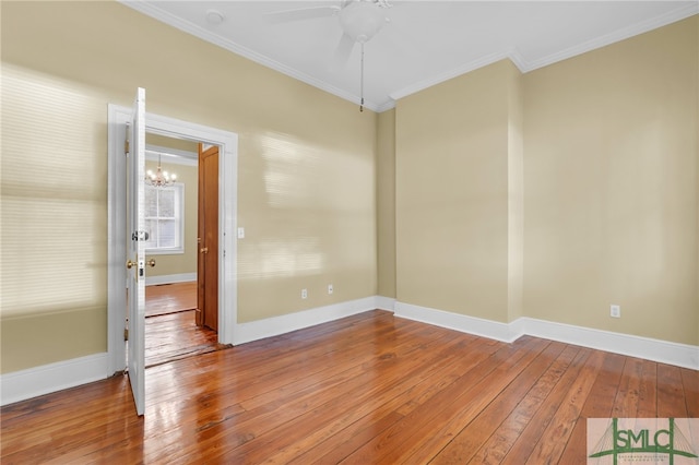 unfurnished room featuring hardwood / wood-style flooring, ornamental molding, and ceiling fan with notable chandelier