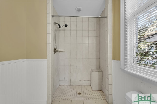 bathroom featuring toilet, tile patterned flooring, and a tile shower