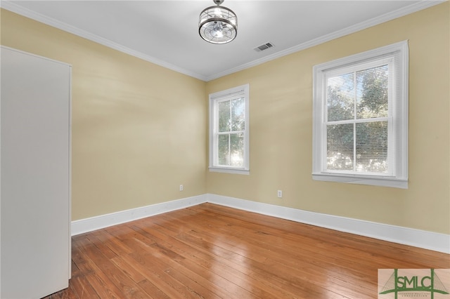 spare room featuring hardwood / wood-style flooring, a healthy amount of sunlight, and crown molding