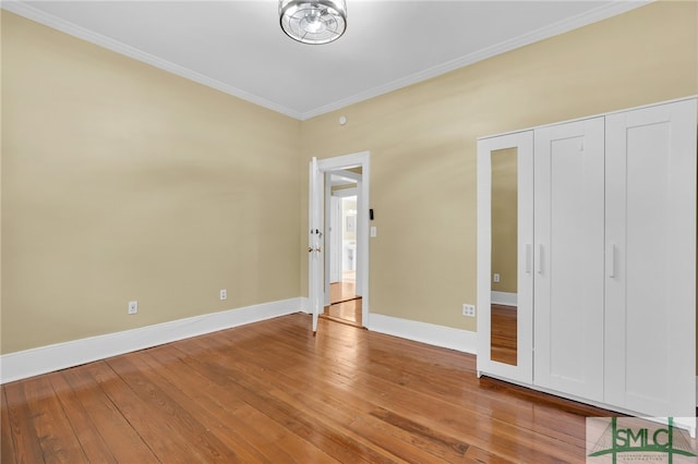 unfurnished bedroom with hardwood / wood-style floors and crown molding