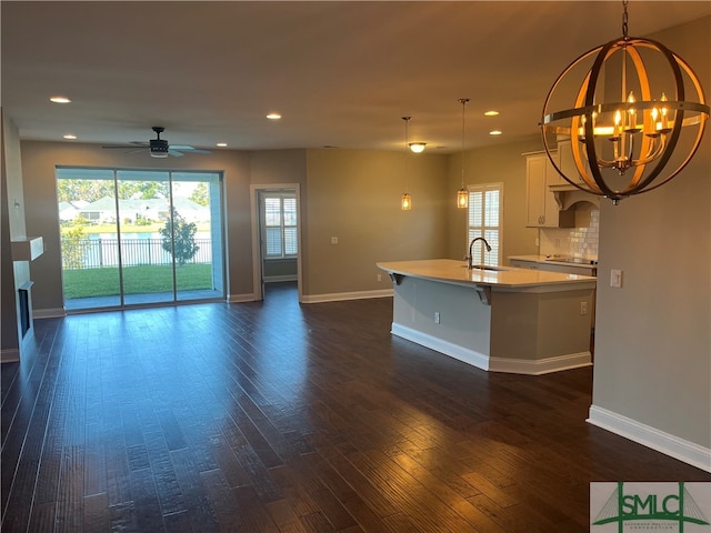 unfurnished living room featuring sink, dark wood-type flooring, and ceiling fan with notable chandelier