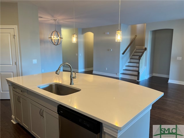 kitchen with stainless steel dishwasher, sink, an island with sink, and hanging light fixtures