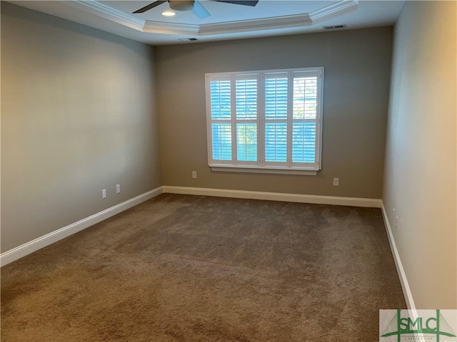 empty room with ornamental molding, ceiling fan, dark carpet, and a raised ceiling