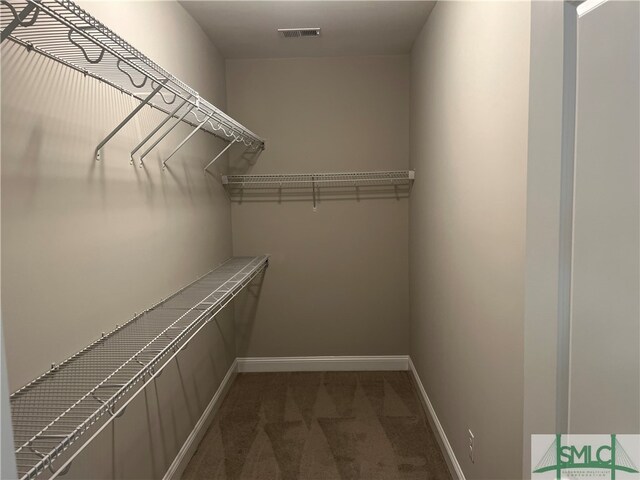 walk in closet with dark carpet