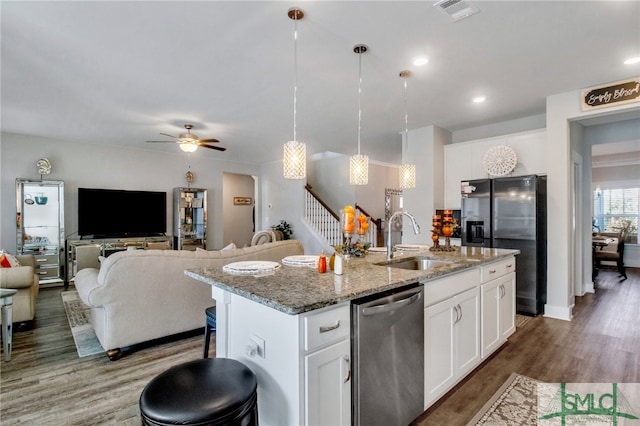 kitchen with stainless steel dishwasher, sink, white cabinetry, and a center island with sink