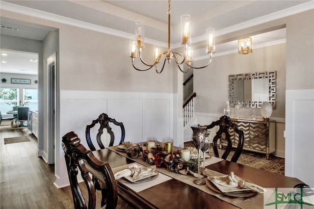 dining area featuring crown molding, hardwood / wood-style flooring, and a notable chandelier