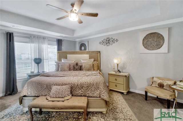 carpeted bedroom with a tray ceiling and ceiling fan