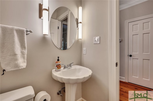 bathroom with crown molding, wood-type flooring, and toilet