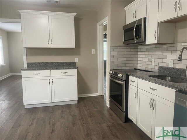 kitchen with tasteful backsplash, appliances with stainless steel finishes, sink, white cabinets, and dark hardwood / wood-style floors