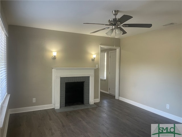 unfurnished living room with ceiling fan, a brick fireplace, and dark hardwood / wood-style flooring