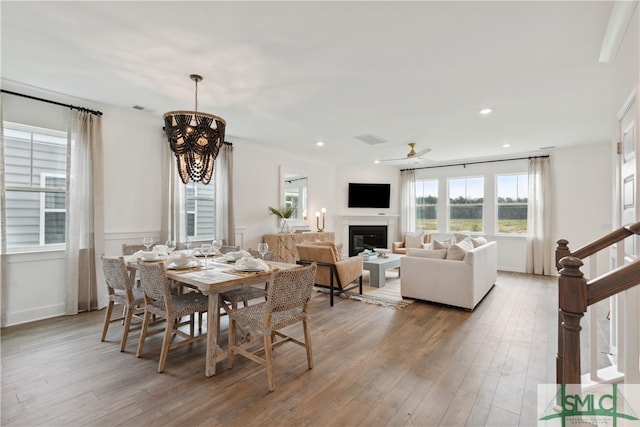 dining room featuring wood-type flooring, ceiling fan with notable chandelier, and ornamental molding