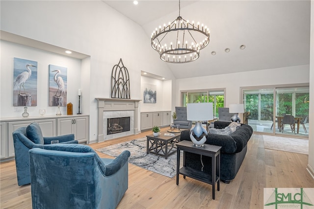 living room featuring a fireplace, high vaulted ceiling, an inviting chandelier, and light wood-type flooring