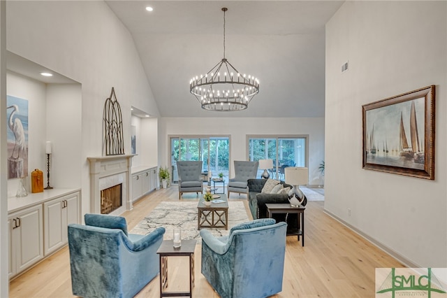 living room with a chandelier, high vaulted ceiling, and light hardwood / wood-style flooring