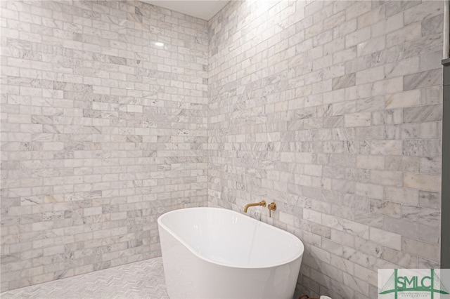 bathroom with a washtub and tile patterned floors