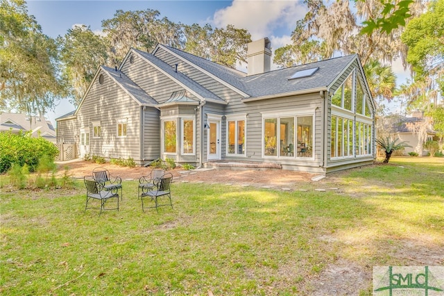 back of house with a lawn, a sunroom, and a patio