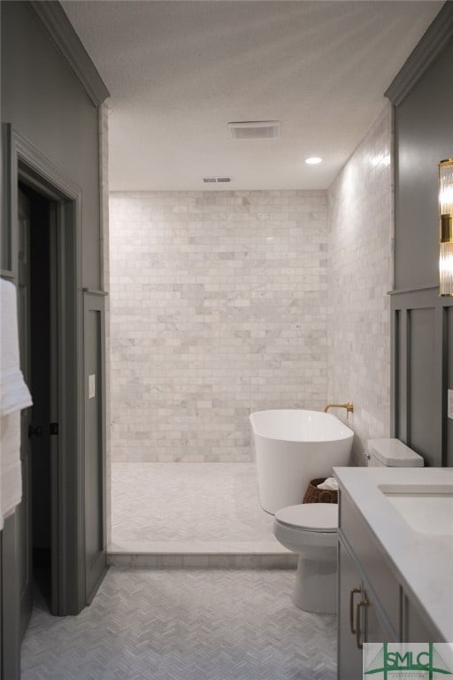 bathroom featuring a bathtub, a textured ceiling, vanity, tile walls, and toilet