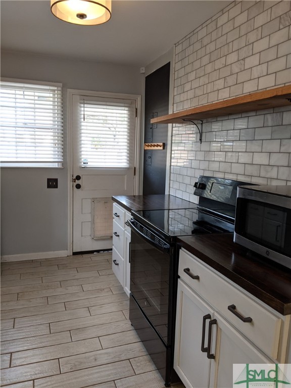 kitchen featuring black / electric stove, light hardwood / wood-style flooring, white cabinetry, and tasteful backsplash