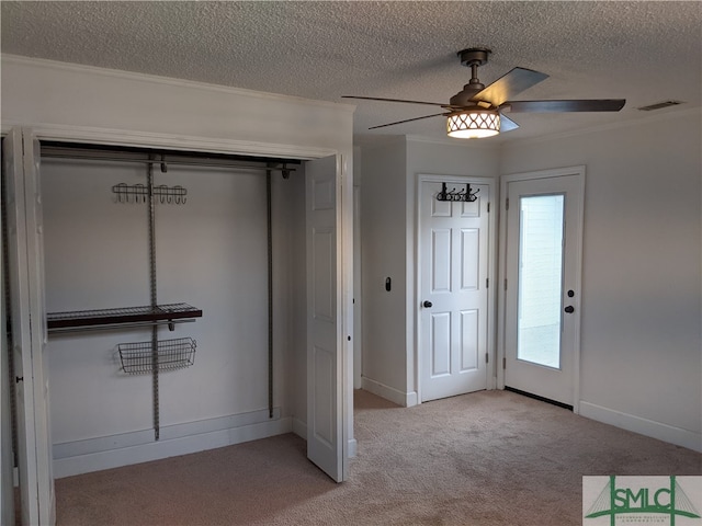 foyer with ceiling fan, light carpet, a textured ceiling, and crown molding