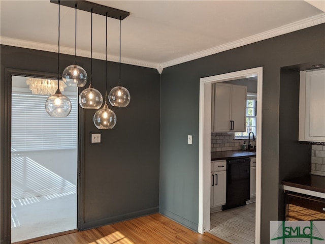 kitchen with black dishwasher, tasteful backsplash, hanging light fixtures, light wood-type flooring, and crown molding